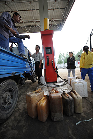 几户农民在拿著大大小小的油桶在黑龙江省方正县高号加油站加柴油.